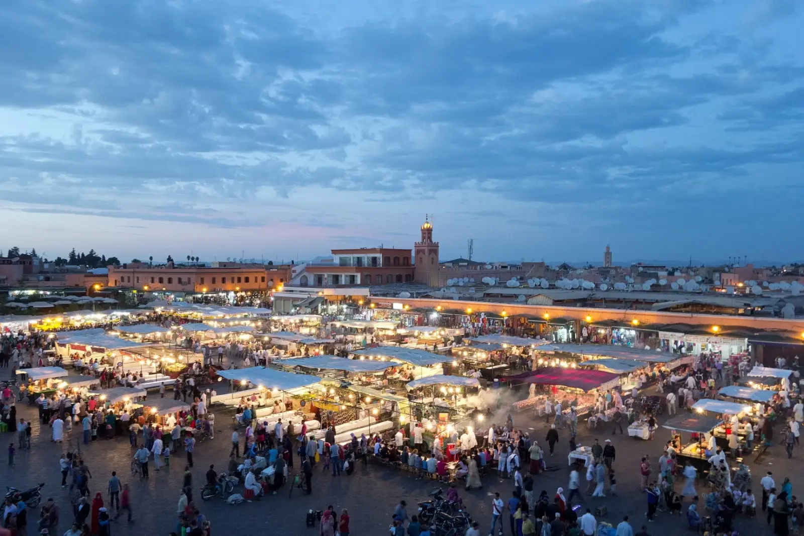 Jemaa el-Fna square in Marrakech at dusk, with illuminated stalls and crowds