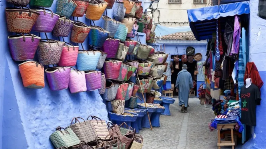 Colorful woven baskets and crafts displayed in a blue Chefchaouen lane